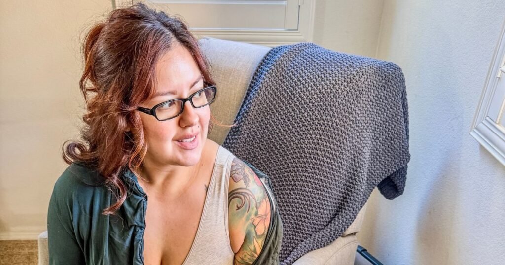 image of woman (karissa) in a green shirt and grey bra sitting and looking out a window