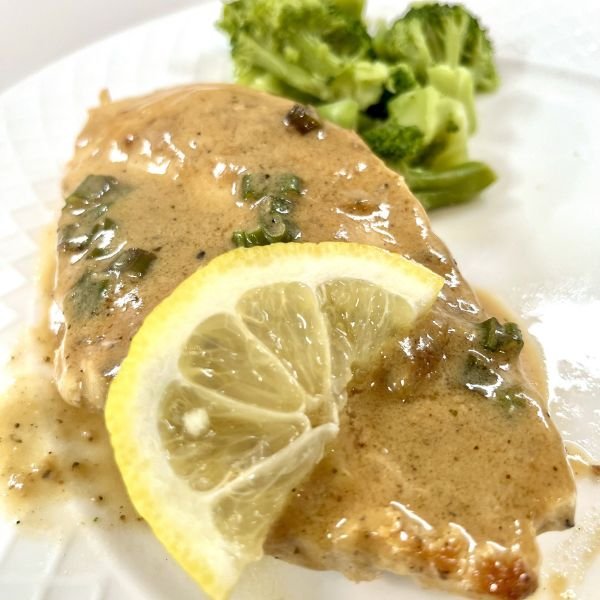 close up image of a creamy chicken with a lemon slice on top next to broccoli florets - part of easy dinners for busy moms article