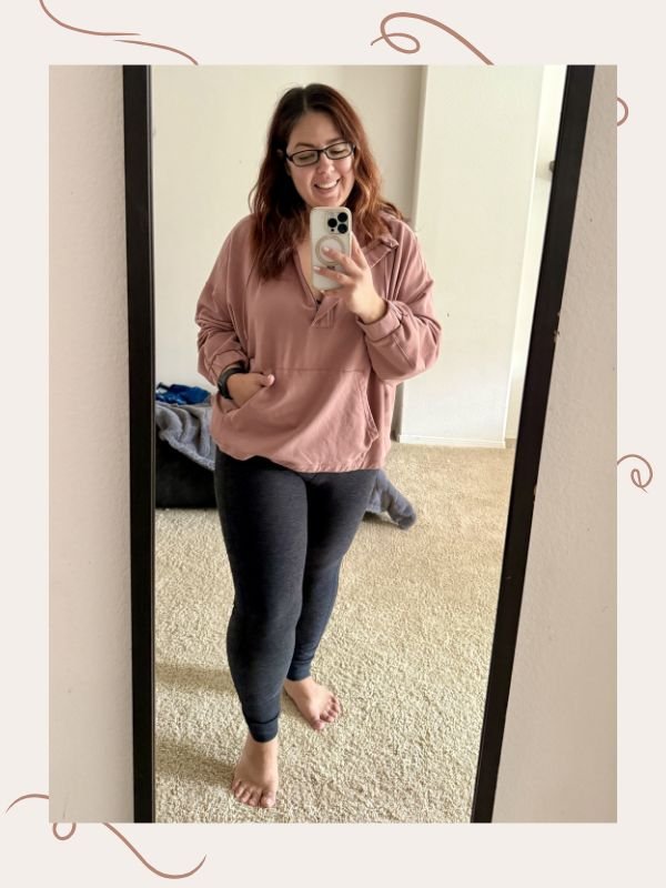 mirror selfie image of woman wearing pastel pink oversized hoodie and leggings