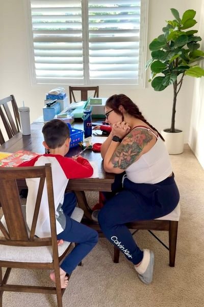 Mom doing homework with her son at a messy dining table