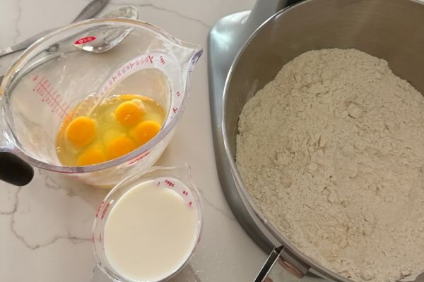 Baking ingredients on counter showing eggs, milk, and flour