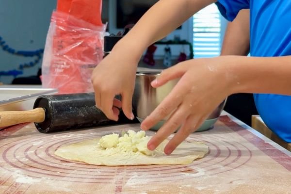 image of dough ball rolled out into a flat - tortilla like shape while being filled with cheese