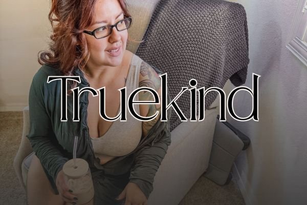 Image of woman wearing a grey Truekind bra while sitting and looking out window and text overlay that reads "Cozy "Truekind"