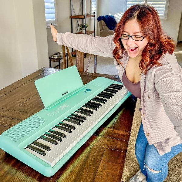 image of Karissa looking excited while standing next to a piano keyboard on dining table