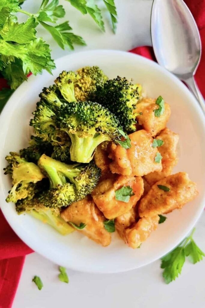 flat lay image of sheet pan buffalo chicken on plate with broccoli