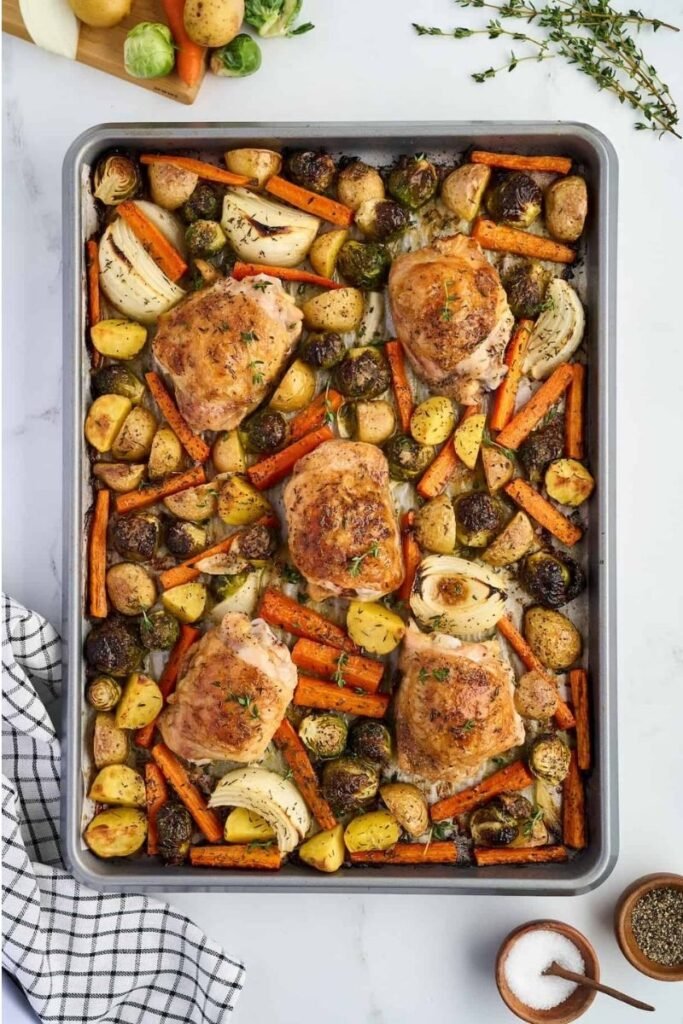 flatlay image of chicken thighs and veggies on a sheet pan by living chirpy
