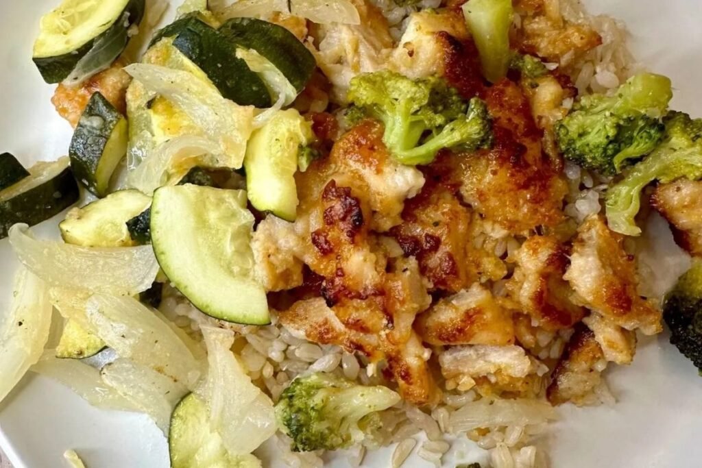close up image of chicken and veggies served on rice on white plate