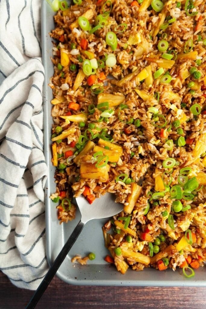 flatlay image of pineapple fried rice sheet pan recipe by the sassy foodie - styled with pan and off white linen